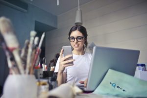 woman with glasses looking at phone in office