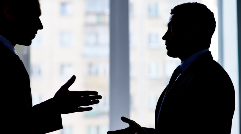 two silhouettes of men with formal attire discussing